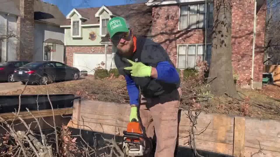 Ronnie Flaherty with a chainsaw beside a pile of cut brush and timbers