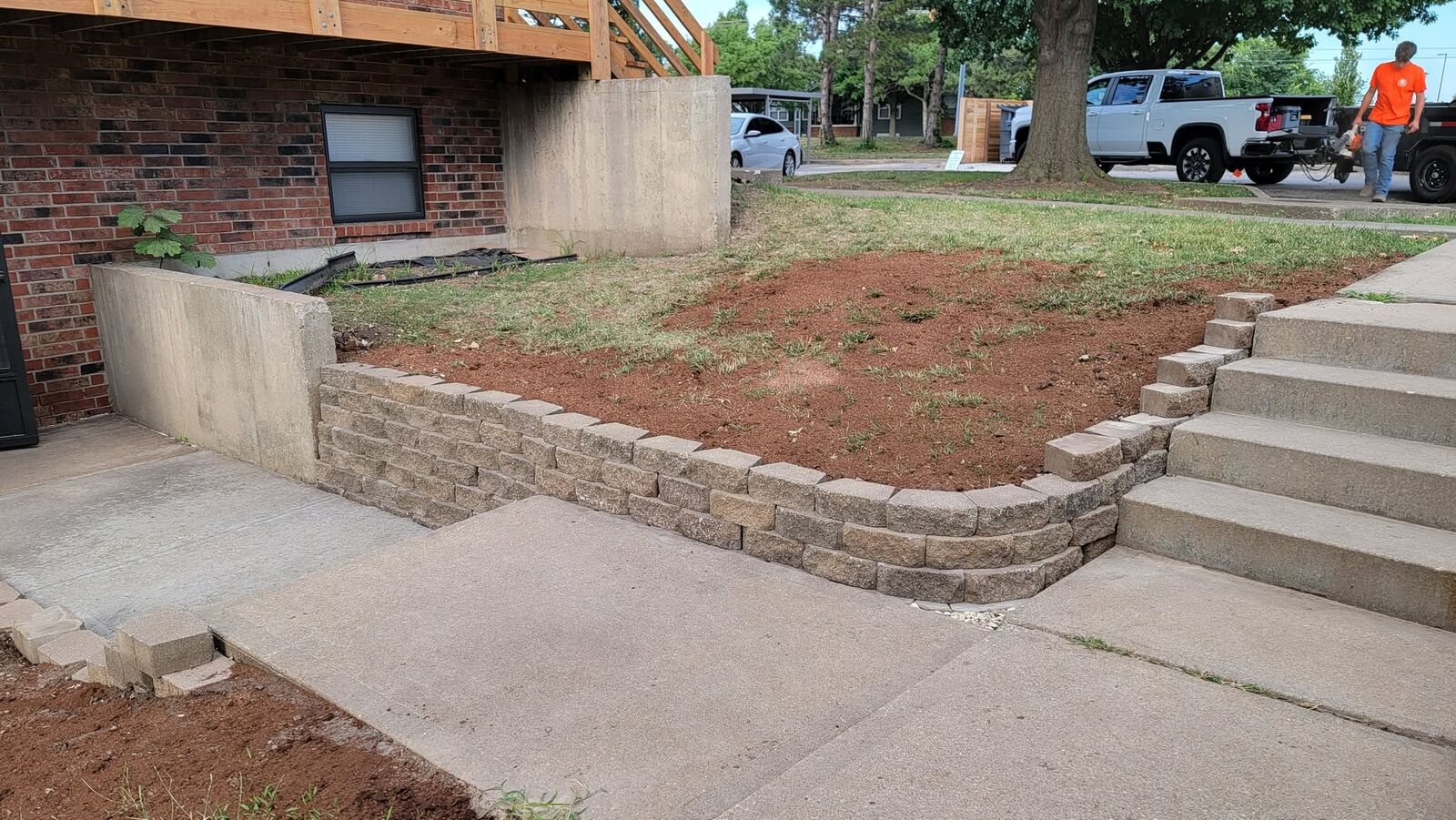 Finished curved block retaining wall in front of a brick house